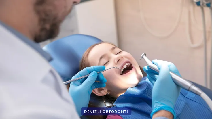 Muayene koltuğunda dişleri kontrol edilen çocuk