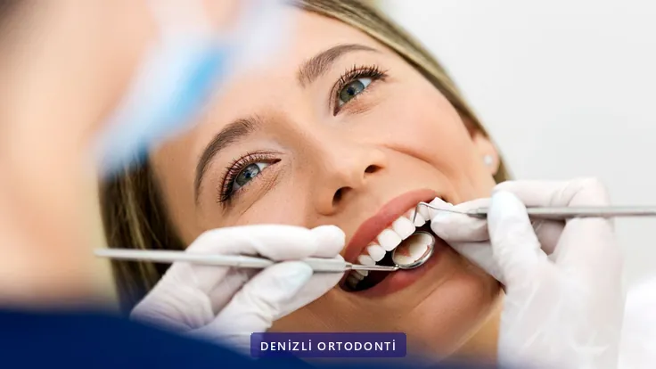 Muayene koltuğunda dişleri ayna ve sondla incelenen hasta